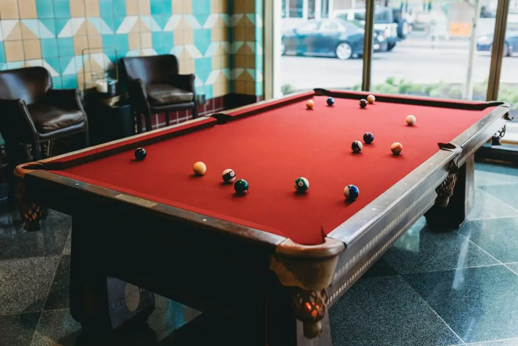 a red pool table in a room with chairs