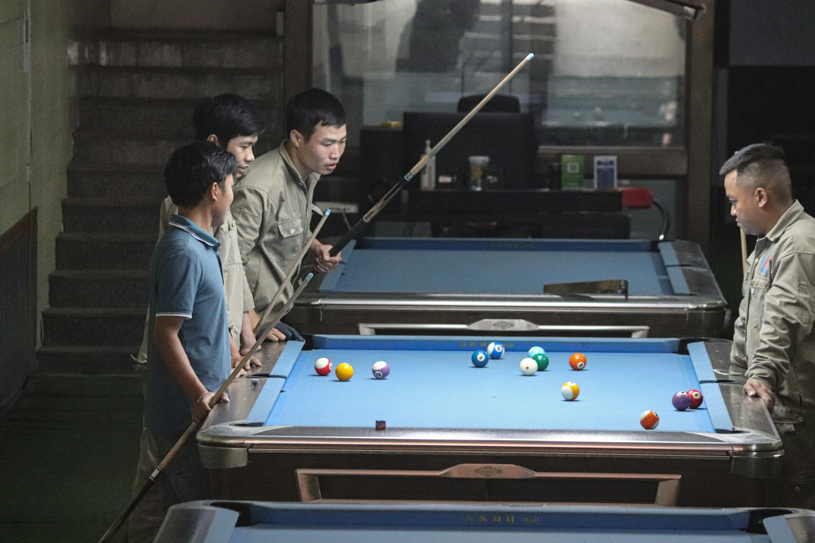 a group of men standing around a pool table